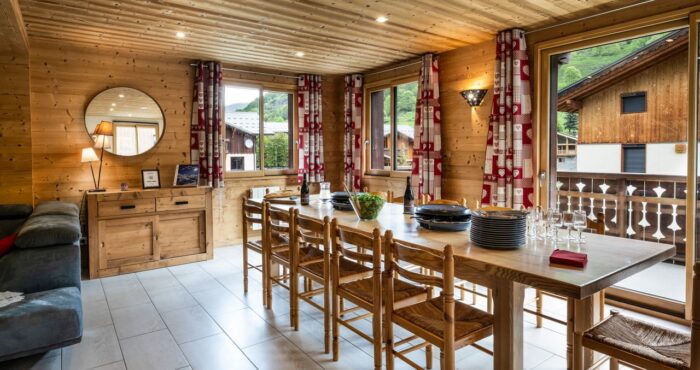 Living room with large dining table and bay windows in chalet Snow Pearl