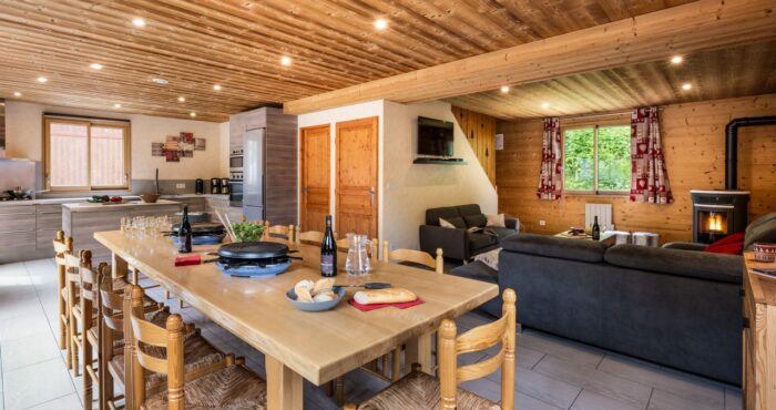 Living room with large dining table , sofas and fire place in chalet Snow Pearl